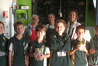 Parents and staff with students in the school canteen holding reusable items like paper straws and bamboo spoons
