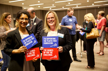 Two ladies at a corporate indoor event holding up signs which read 
