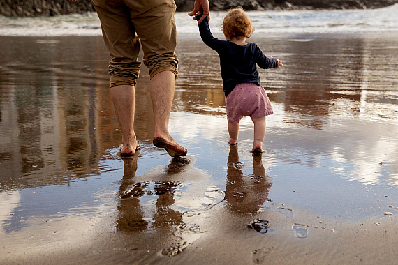 man and child walking on a beach